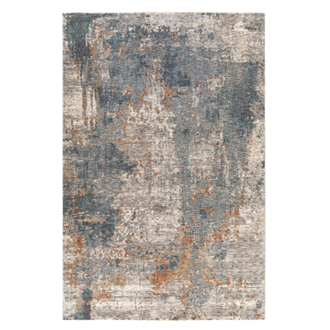 The Candice Machine Woven Rug features a contemporary, medium pile with an abstract, distressed pattern in muted gray, blue, and rust orange. Its uneven color blend creates a textured, weathered look inspired by worn stone or aged paint.