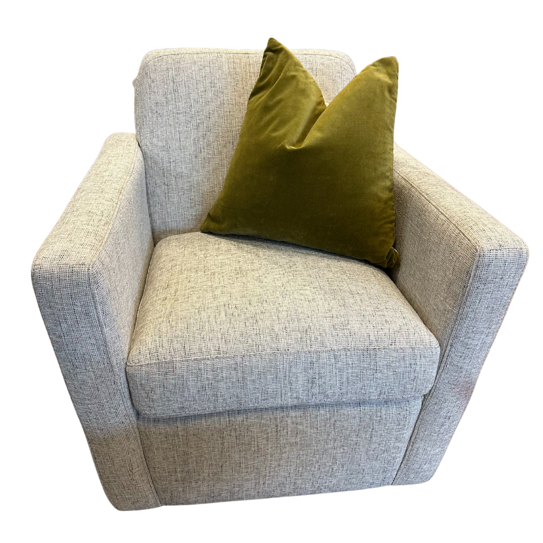 A modern light gray armchair with square arms and a boxy shape is shown against a plain white background, featuring the Sally Green Velvet Throw Pillow filled with luxury down and feather.