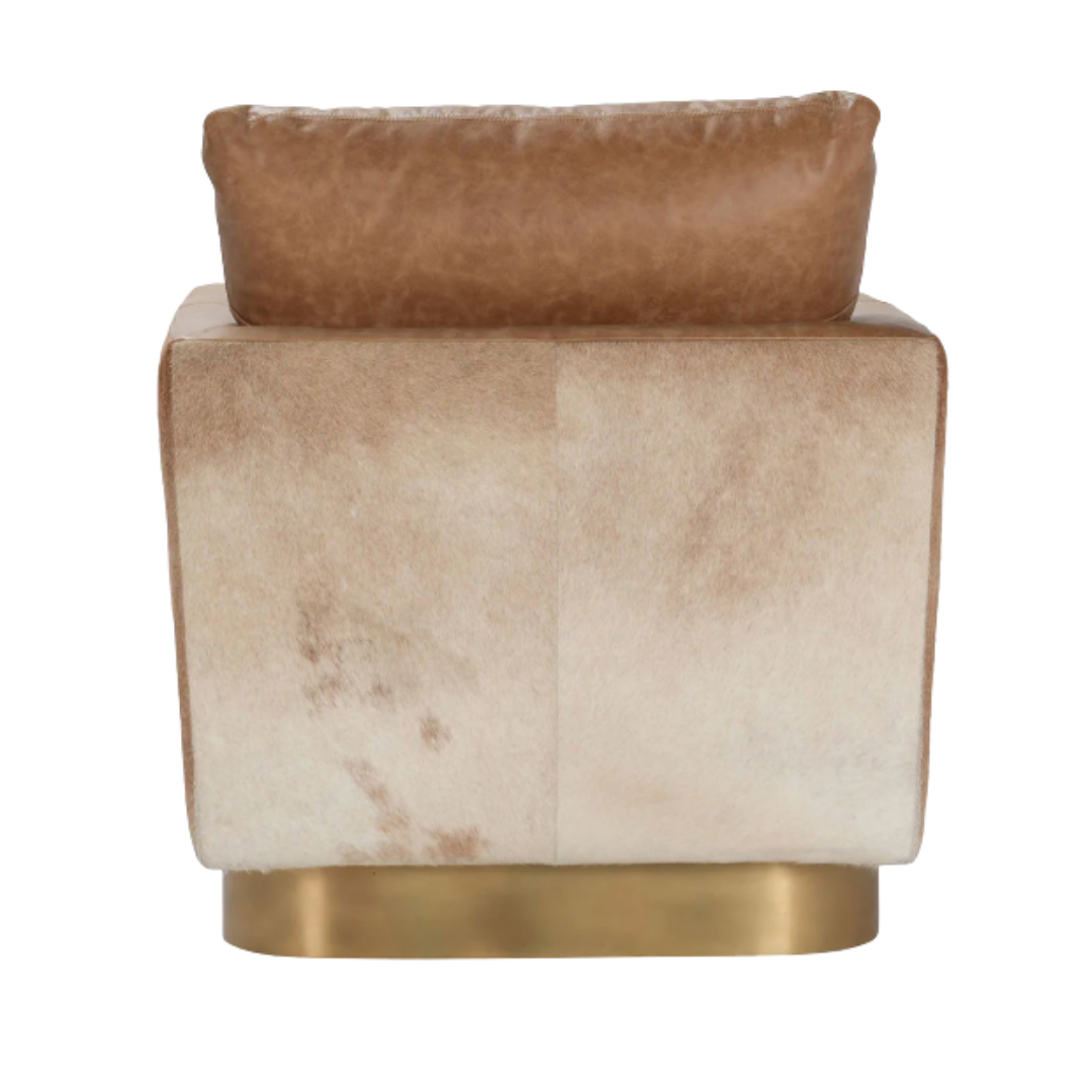 The Velancia Hide & Leather Swivel Chair exudes modern glamour with its square ottoman, featuring a soft top grain leather cushion. Its metallic base boasts a brass finish, and the side panel showcases a subtle gradient from light to dark beige, enhancing its sophisticated appeal.