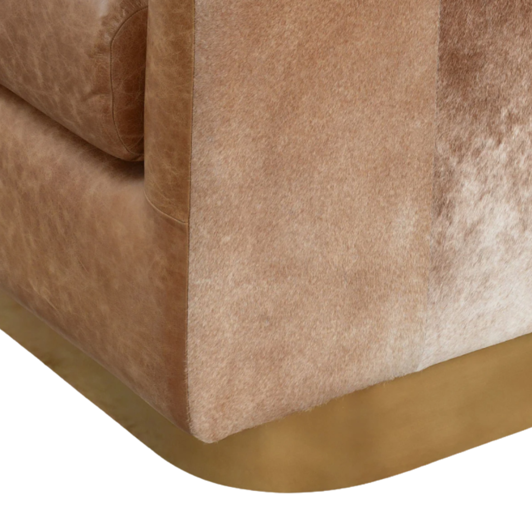 A Velancia Hide & Leather Swivel Chair presents a glamorous close-up of plush, light brown suede-like textured fabric with subtle shade variations, complemented by rounded edges and a gold metallic base—an ideal luxury addition alongside any top grain leather piece.