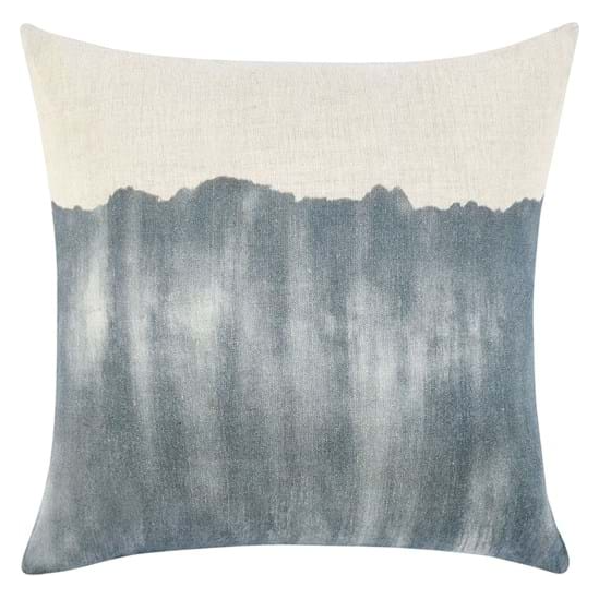 Introducing the Indy Natural and Denim Throw Pillow, a square decorative pillow that features a gradient design. The top part of this exquisite pillow is off-white, seamlessly transitioning into a dark grayish-blue color towards the bottom. The gradient showcases an uneven, natural edge reminiscent of a watercolor pattern. Filled with luxurious down and feather inserts, the textured fabric appears to be made from linen or a linen blend.