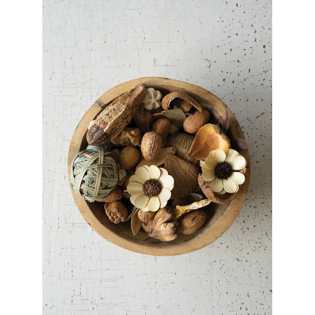 A Natural Filler wooden bowl rests on a textured white surface, showcasing assorted nuts, seed pods, a woven ball, and two cream-colored artificial flowers for an earthy, rustic display.