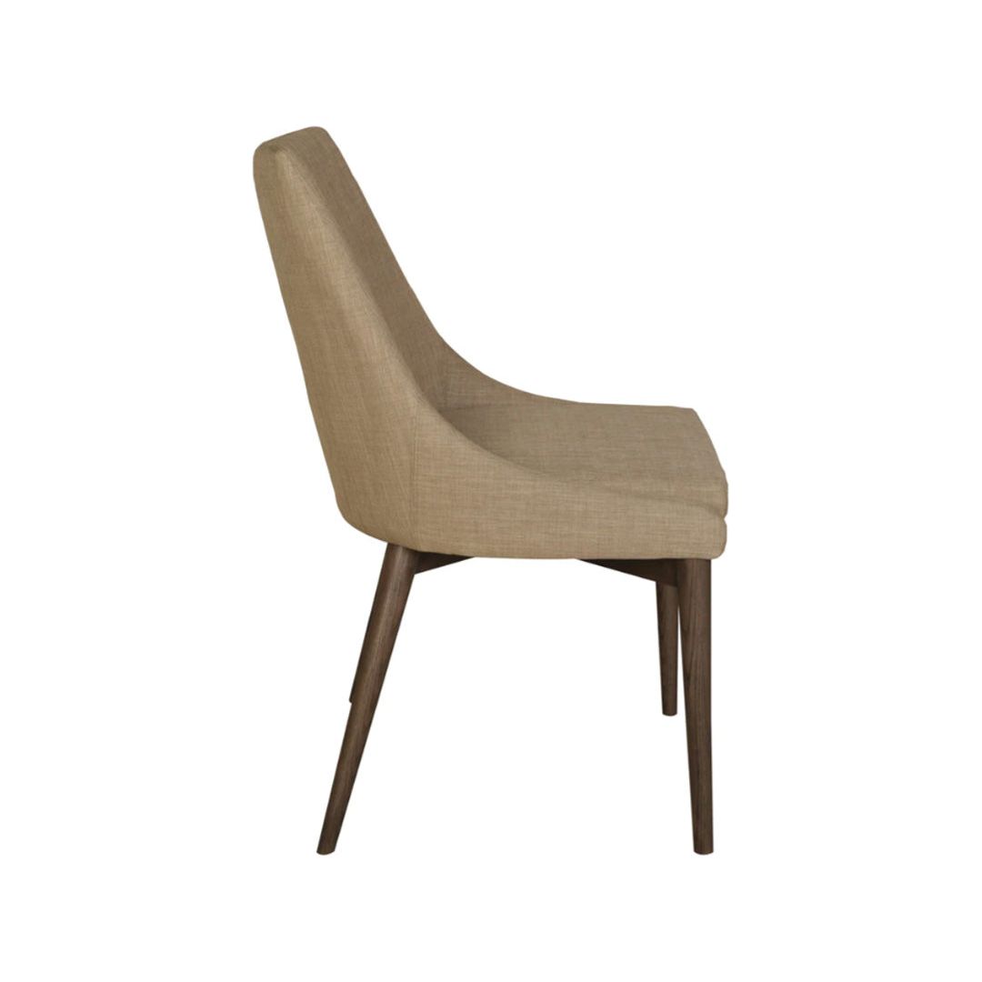 The Franny Dining Chair, Beige features a modern, versatile design with a beige upholstered seat and backrest. It has a slightly curved contour for comfort and support. Standing on four slender, tapered dark wooden legs, the chair’s profile is simple yet elegant. Photographed against a plain white background.
