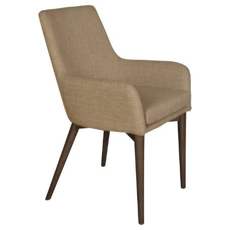 The Franny Arm Dining Chair is a modern upholstered chair with light brown fabric and a high, slightly angled backrest. The chair has cushioned seating and slender, tapered ash wood legs in a dark brown finish. The armrests are integrated into the backrest and have a smooth, curved design, perfect for any dining table setting.
