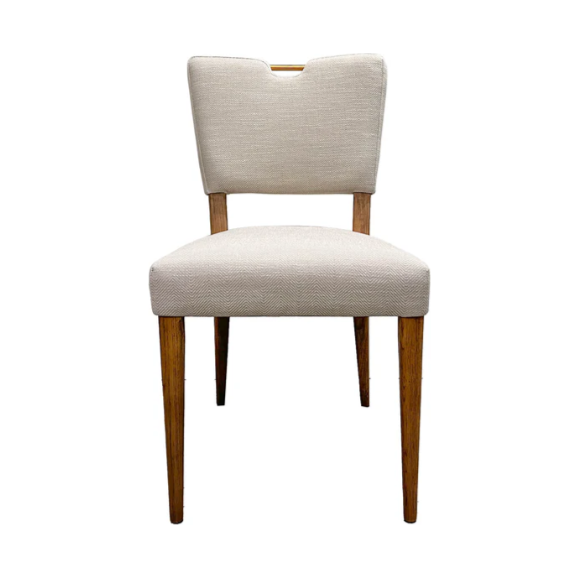 A front view of the Arden Gold Handle Dining Chair, featuring beige upholstery, straight tapered solid ash wood legs, and a signature wooden handle accent atop the backrest. The background is plain white.