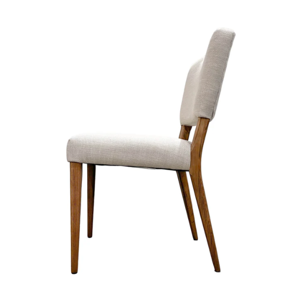 The Arden Gold Handle Dining Chair features a light beige upholstered seat and backrest, four angled solid ash wood legs, and a slightly reclined minimalist profile—shown in elegance against a plain white background.