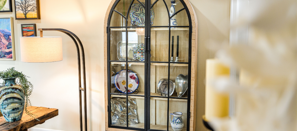 Elegant arched glass display cabinet styled with decorative plates and silver accents, designed by Northern Colorado interior design team Change Everything