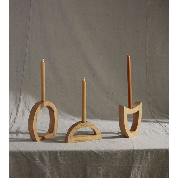 Three Wooden Arch Candleholders, mirroring lunar phases with a circle, semi-circle, and squared arch design, elegantly hold earth-toned taper candles in brass inserts on a neutral fabric for a minimalist display.