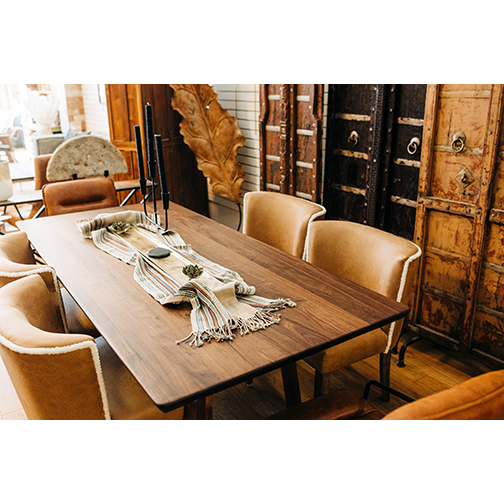 A cozy dining area featuring a wooden table with a decorative runner and two Shearling Dining Chairs. In the background, rustic metal and wooden decorative doors create a vintage ambiance.