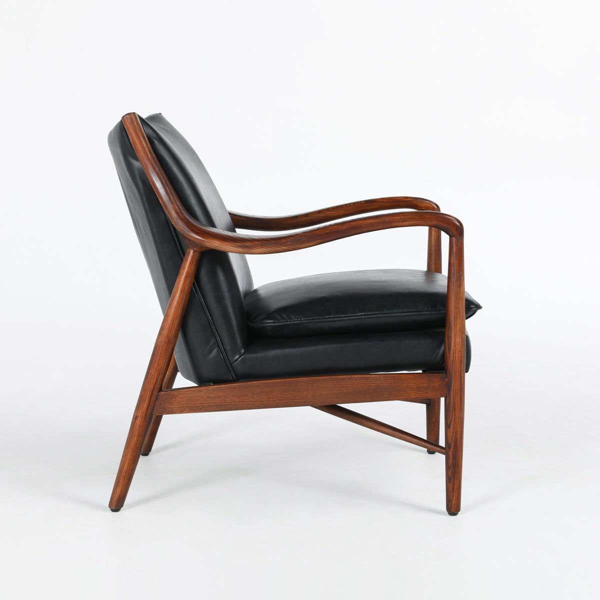 A modern walnut Benson Mid-Century Leather Accent Chair with a curved frame and genuine black leather cushioning. The chair features smooth, flowing wooden arms and legs in a rich, dark brown finish, providing both elegance and comfort. Set against a plain white background.