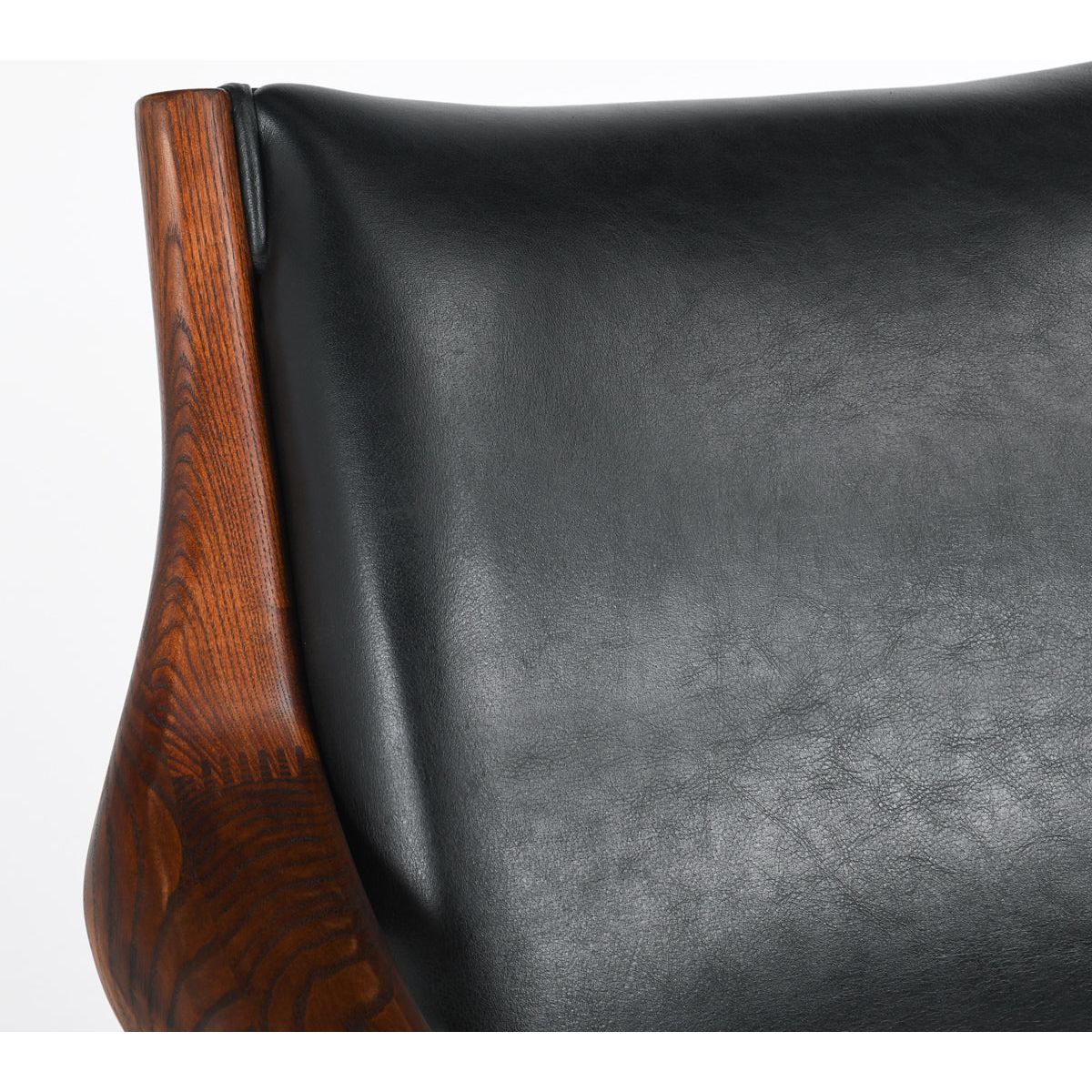 Close-up of a Benson Mid-Century Leather Accent Chair featuring a sleek black leather back and a richly textured walnut frame with visible grain, emphasizing the high-quality materials and craftsmanship.