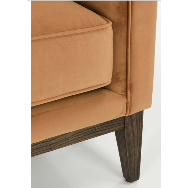 Close-up of a modern Amber Accent Chair corner showing a plush, tan cushion and a dark wooden leg with a distinct, angular design. The fabric appears soft and woven upholstery, emphasizing both comfort and style.