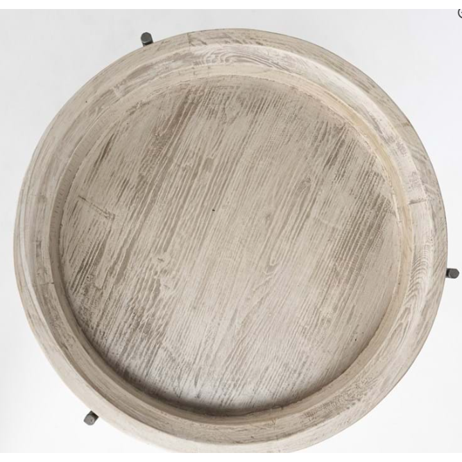 Top view of a Lucinda Nesting Table featuring a round wooden tabletop with a light, weathered finish. The table displays a slightly raised edge and distinct wood grain patterns. Three black metal legs, which enhance the rustic design, are partially visible at the edges of the image.