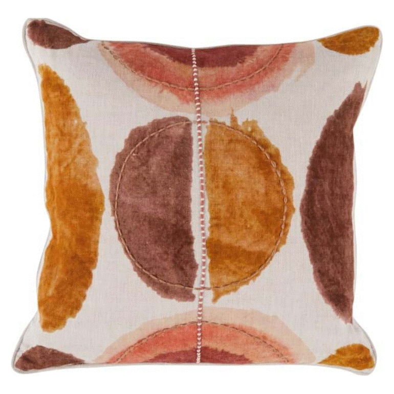 The Solar Clay pillow features a white background with abstract circular patterns in rust, orange, and brown. It includes a plush feather down insert, visible center stitching, and matching colored shapes along the edges for added style.