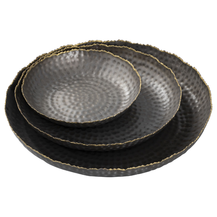 The Leonard Tray set includes four round metal plates with a grey textured, hammered finish and scalloped edges. Gold rims accent the dark gray plates for an elegant look. They range in size and nest neatly, creating a decorative stacked display.