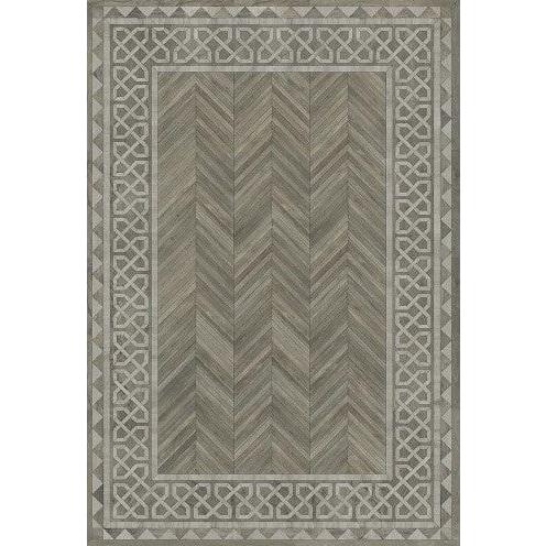 The Dila Vinyl Rug is a rectangular piece featuring a central herringbone pattern in shades of gray. Its border displays an intricate geometric design that incorporates interlocking shapes and diamond motifs, offering a timeless and elegant appeal with its symmetrical layout.