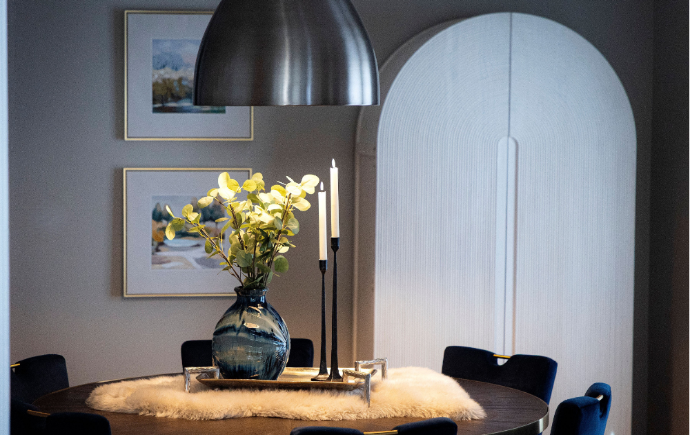Elegant contemporary dining space with a round wood table, brushed metal pendant light, soft textures, and modern artwork