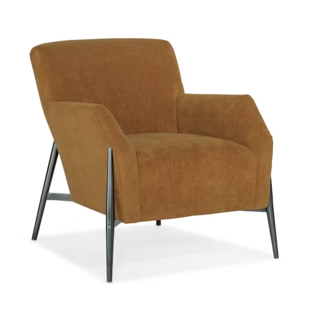 The Sienna Luxe Custom Accent Chair features soft cognac upholstery, angled dark-finish metal legs, a low wide backrest, gently sloped arms, and thick cushioning for a modern look with sleek comfort.