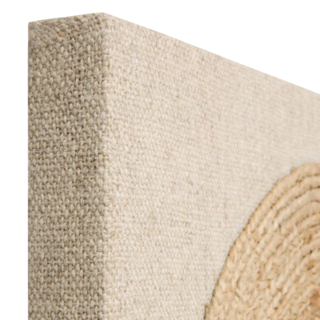 Close-up of the top left corner of a textured beige canvas with raised circular detail, the Bellmont Braided Wool Boho Wall Art adds organic texture and earthy tones for a natural, rustic touch to any décor.