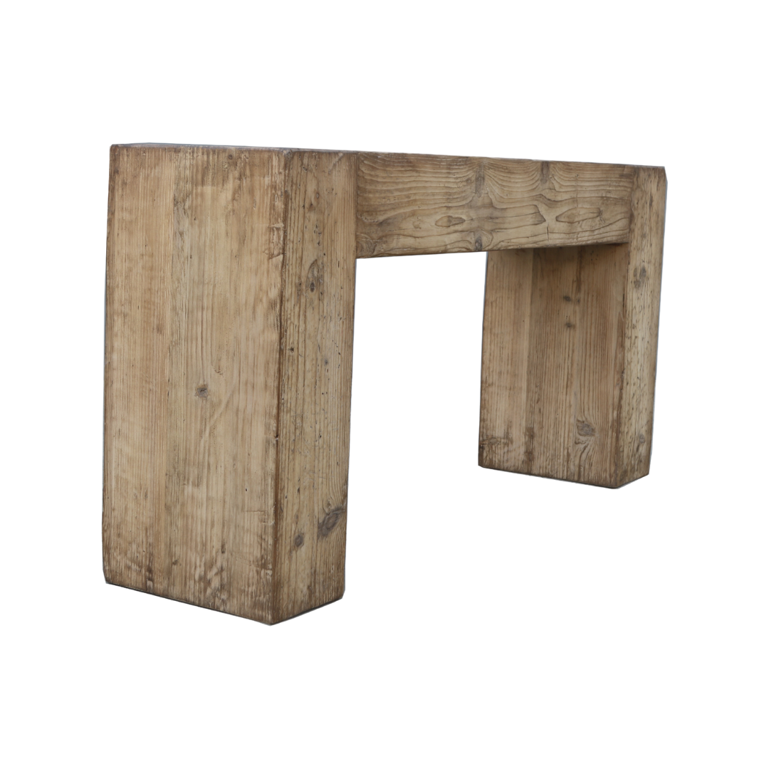 The Broadwell Console Table features a rustic design crafted from thick reclaimed pine planks, showcasing visible grain patterns and knots. Its simple rectangular shape with two wide legs and a flat top has an aged finish for added charm, set against a plain white background for an eco-friendly appeal.