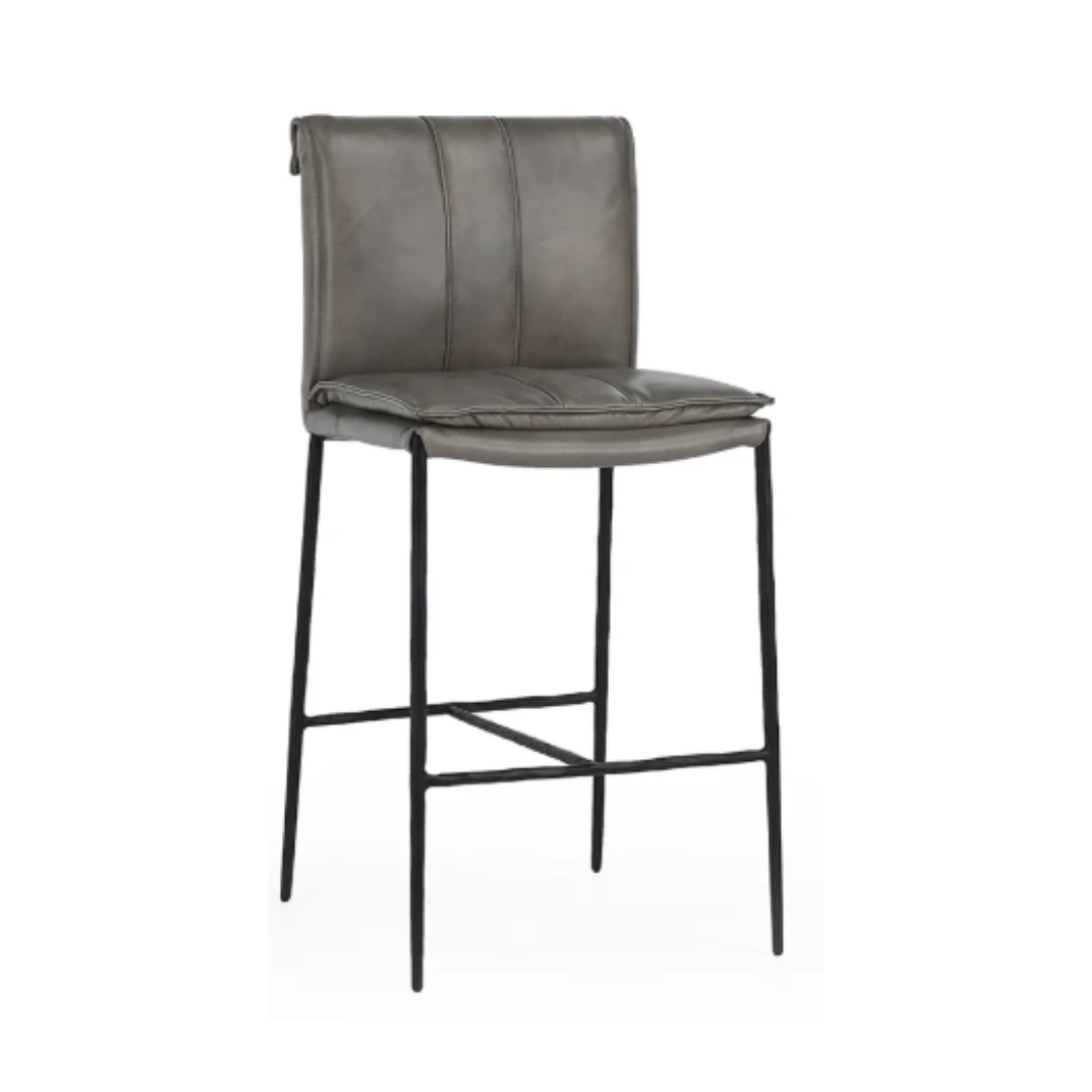Discover the Calder Leather Counter Stool, a contemporary marvel with a gray cushioned leather seat and vertically stitched backrest. Featuring thin black metal legs and a sculptural frame with an integrated footrest, it embodies sleek modern design.
