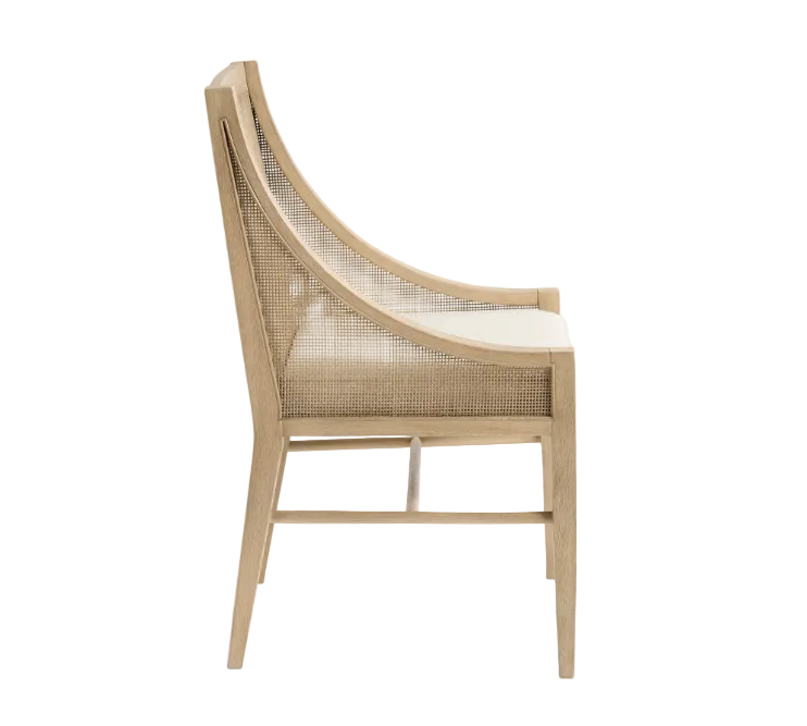 A light natural wood dining chair with a curved backrest, woven cane seat, and cream cushion, shown from a side profile view against a plain white background.