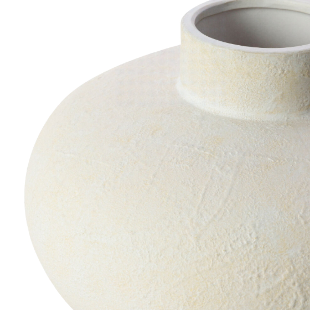 A close-up of the Cavera White Ceramic Vase shows its wide, round body and small circular opening. The matte off-white finish has subtle tonal variations, highlighting the vase's slightly rough, sculptural, handmade texture.