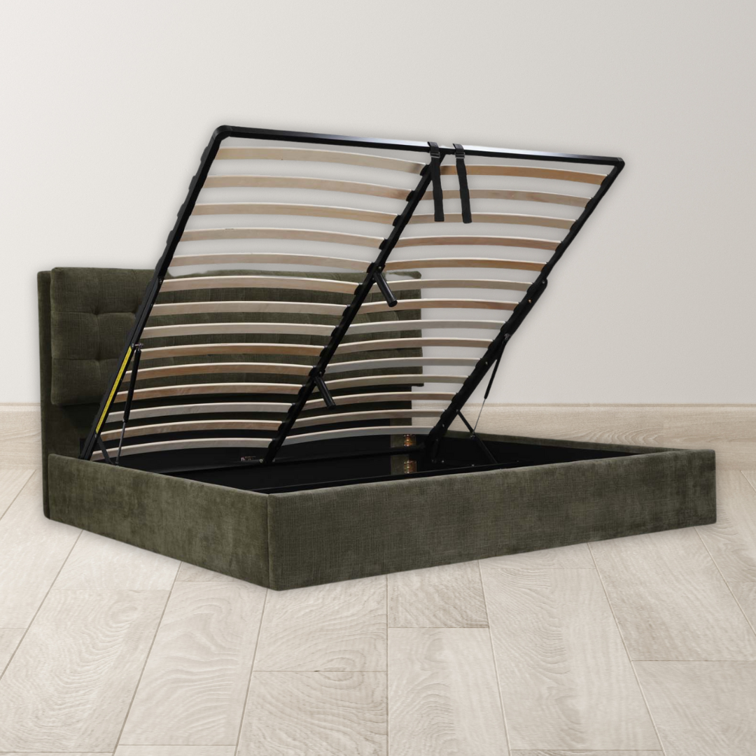 The Corveline Green Storage Bed features a green upholstered finish, hydraulic lift storage, a tufted headboard, and slatted base for ample under-bed space. It's shown on a light wood floor against an off-white wall.