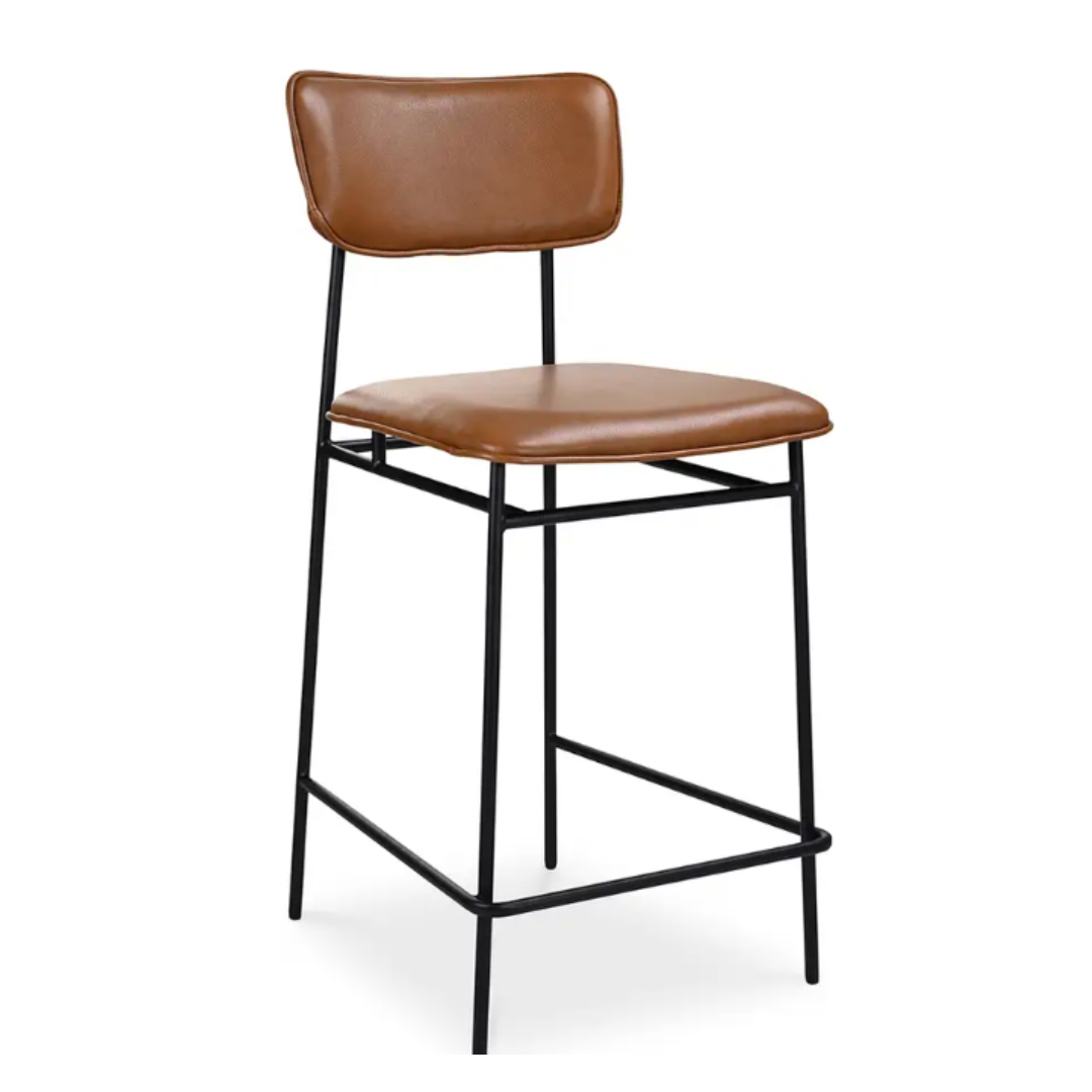 The Elara Leather Counter Stool showcases caramel leather upholstery for modern minimalism, featuring a brown cushioned seat and backrest. Its sleek black metal frame with slender legs and a stability bar highlights contemporary elegance with clean lines.