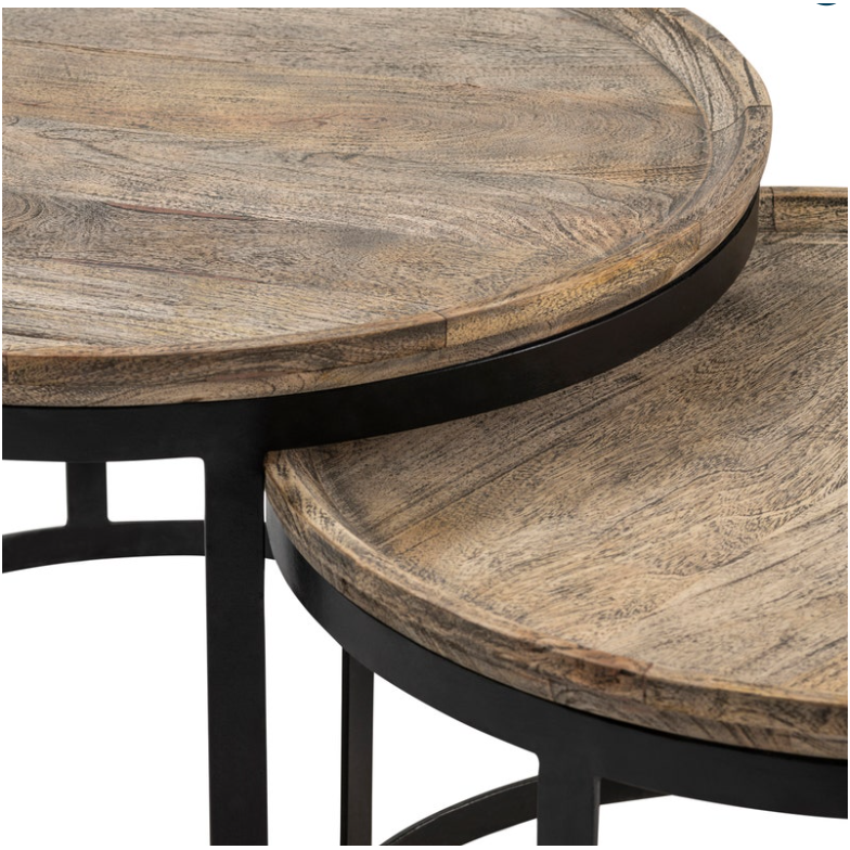 Close-up image of two Fillmore Nesting Coffee Tables with a natural Mango wood grain finish. These stylish nesting tables feature black metal frames and are partially stacked, showcasing the upper section of the smaller table fitting neatly beneath the larger one. The wood surfaces have a slightly raised edge.