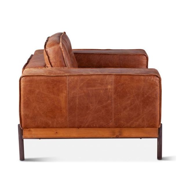 A distressed antique Cocoa leather armchair with a warm brown finish, featuring a plush back cushion and a sleek metal frame that visibly supports the seat. The chair's profile shows its streamlined design and robust construction.