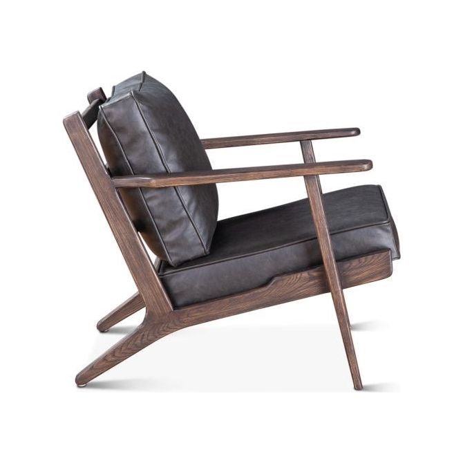 A modern lounge chair with a walnut frame and distressed black leather upholstery. The Dalton Rustic Leather Armchair is showcased in a side view, highlighting its angular design and plush cushions.
