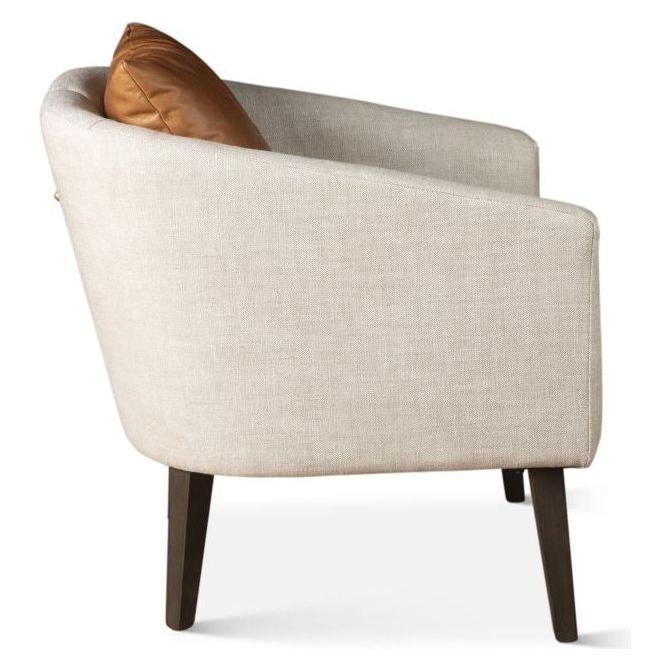 Side view of the Serenity Accent Chair showcasing its light beige upholstery and sleek, dark wooden legs. This chair boasts a curved back, with a brown leather cushion placed on the seat. Its minimalist design emphasizes clean lines and a contemporary aesthetic.