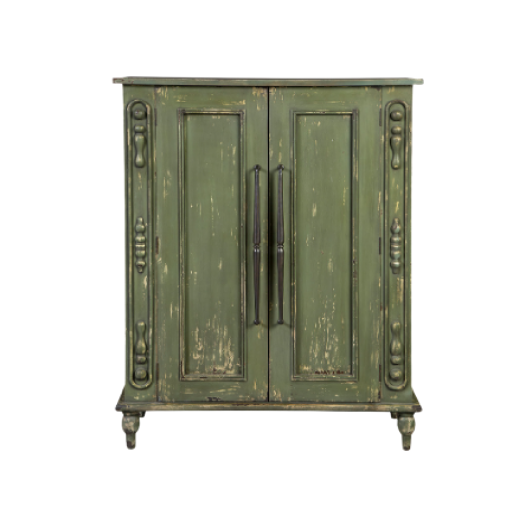 The Lorent Vintage Green Mahogany Cabinet, with its distressed green finish and intricate carvings, exudes functional elegance. It features two black metal handles and stands on four small turned legs. The worn paint adds a charming rustic appearance.
