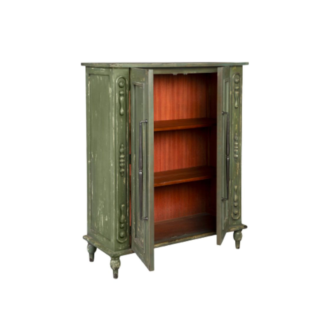 The Lorent Vintage Green Mahogany Cabinet features exquisite carvings and elegant functionality. With one door slightly open, it reveals spacious shelves. Its weathered texture and ornate details, supported by four decorative legs, emphasize its timeless design.