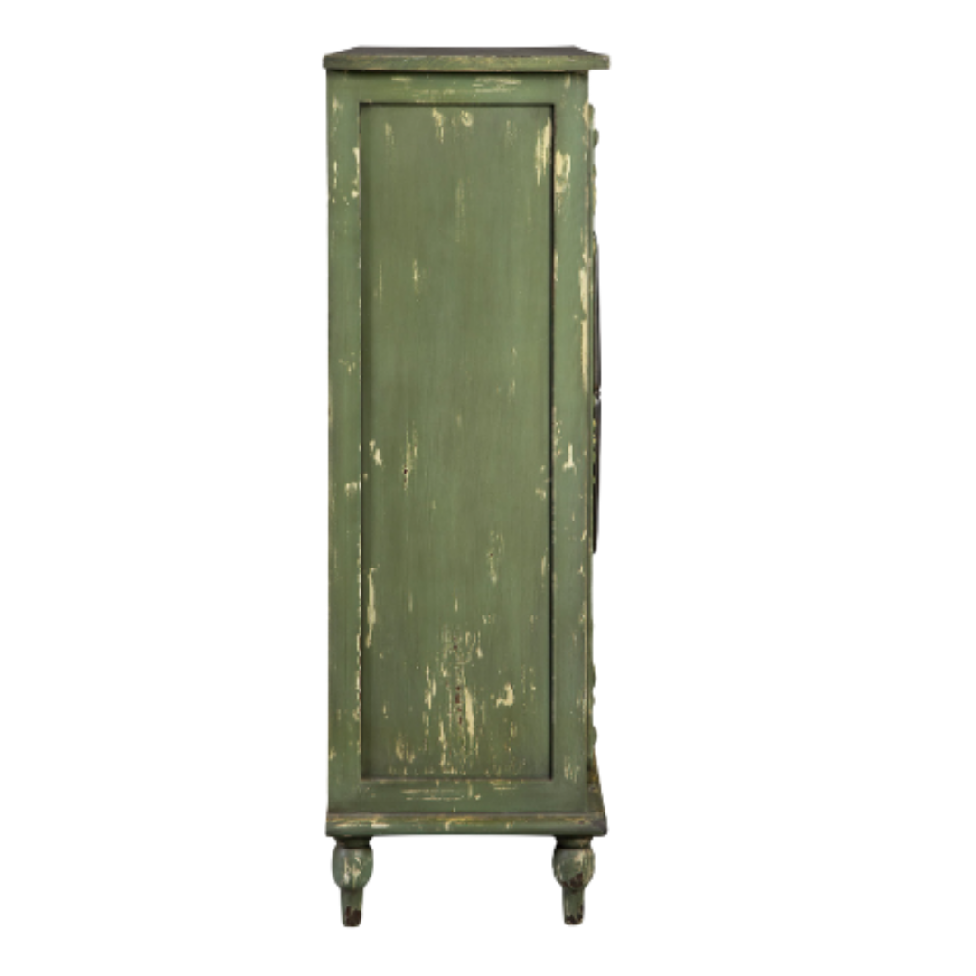The Lorent Vintage Green Mahogany Cabinet is tall and narrow, standing on four ornate carved legs. Its distressed finish reveals faded paint for a rustic, antique look. Functional elegance adds character, while a single front panel exudes nostalgic charm.