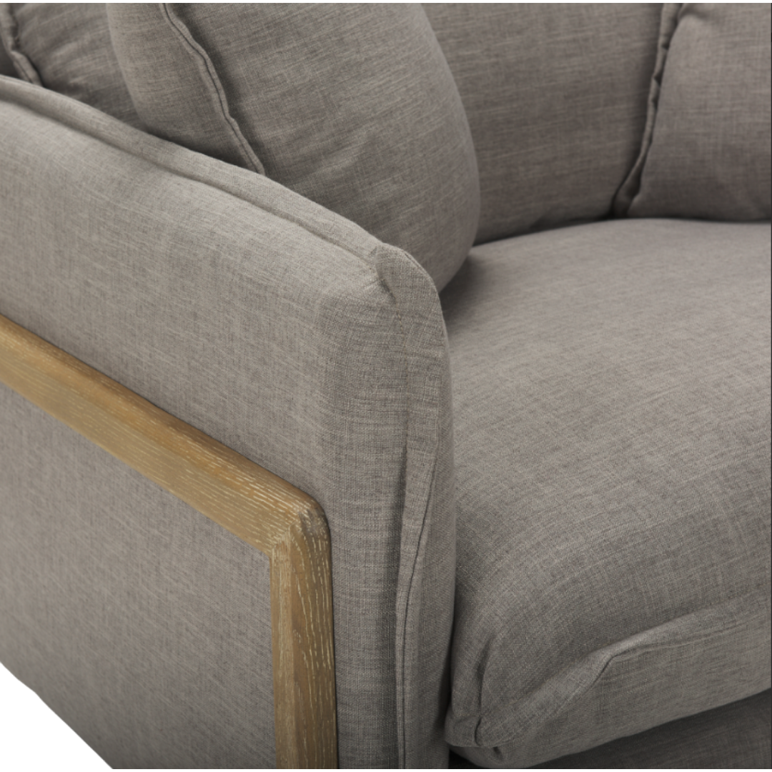 Close-up of the Veyra Plush Upholstered Armchair in Earthy Grey, featuring elegant plush cushions and textured soft fabric. The light wooden panel-framed armrests add a natural touch to its modern comfort, focusing on the corner where armrest and cushions meet.