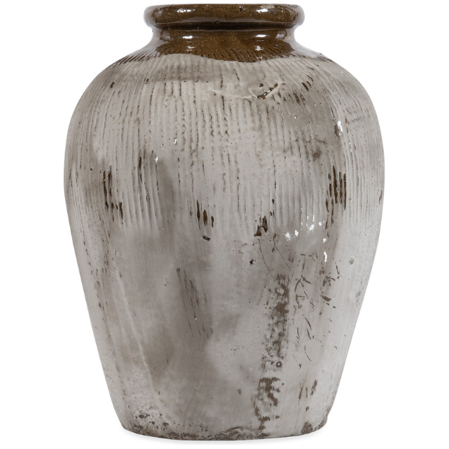 The Rice Wine Jar, Small is a rustic, weathered ceramic vase reminiscent of antique Asian jars. It features a rounded body and a narrow neck with a distressed beige glaze adorned with vertical grooves and brown patches, enhancing its vintage decorative appeal. The surface texture varies across the jar, with some areas appearing more worn and aged than others.