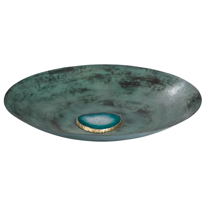 The Josephine Agate features a shallow, round, textured green bowl displaying a smooth, circular blue stone with a gold rim at its center. Its rustic metallic finish and hand-crafted detailing contribute to an earthy aesthetic, while the natural agate serves as a contrasting focal point in this transitional style piece.