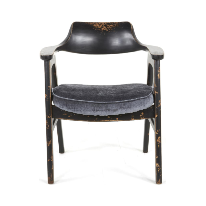 The Vintage Dining Chair in Antique Black/Pewter boasts a mid-century modern design with a slightly curved backrest and armrests. It features a distressed wood look, plush round gray cushioned seat, and worn patches that enhance its rustic charm.
