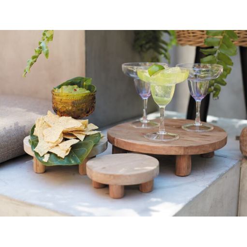 Tejano Riser products made of quality wood elegantly display drinks and snacks on concrete platforms, featuring three margarita glasses on a large stand and tortilla chips in a green leaf on a smaller one. A tiny stand stands ready, while a basket and greenery enhance the rustic charm.