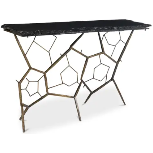 The Nathanial Slate Console Table boasts a contemporary design with a black rectangular top made from organic slate stone featuring uneven edges. The base displays an elaborate, geometric pattern consisting of interconnected brass-finished metal rods that form pentagon and hexagon shapes, creating an artistic and open look.