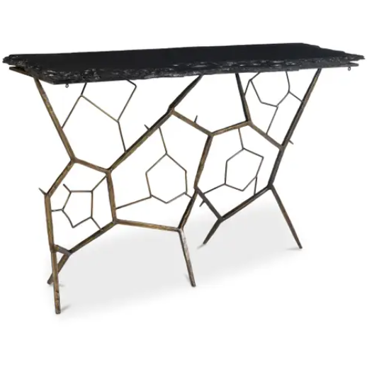 The Nathanial Slate Console Table boasts a contemporary design with a black rectangular top made from organic slate stone featuring uneven edges. The base displays an elaborate, geometric pattern consisting of interconnected brass-finished metal rods that form pentagon and hexagon shapes, creating an artistic and open look.