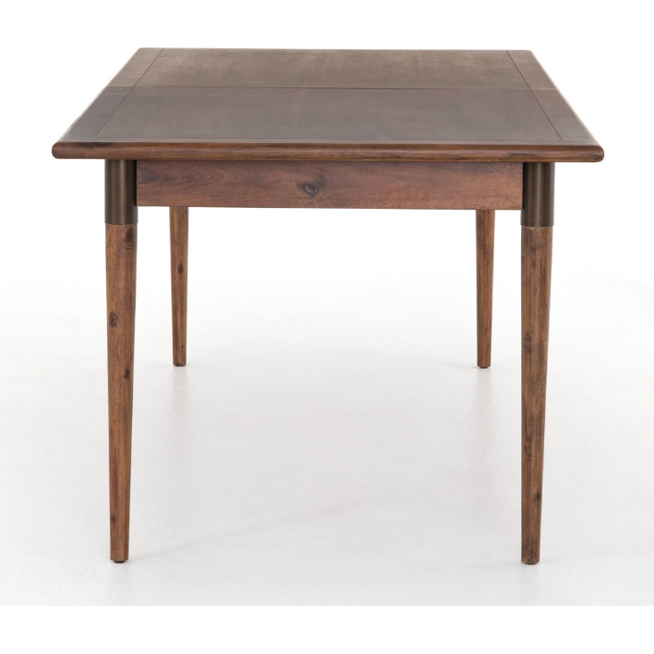 The Teresa Extension Dining Table is a wooden dining table finished in dark brown, toasted walnut. It features a rectangular top and four tapered legs, inspired by Scandinavian modernism. The piece boasts a simple, minimalist design with visible wood grain patterns in acacia wood. Additionally, the white background provides a sharp contrast to the table.