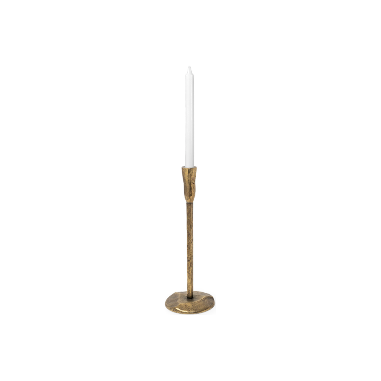 A single tall white taper candle is placed in a slender Levi Gold Iron Candlestick. The candle holder features a circular base and a long, narrow stem with a subtle antique finish. The overall look is simple, embodying rustic elegance, perfect for a classic or vintage aesthetic.