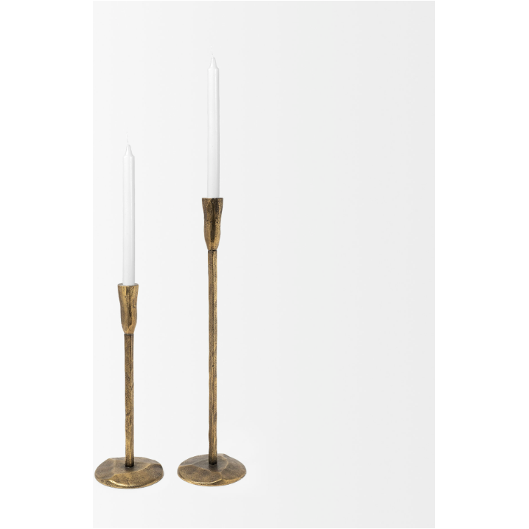 Two lit taper candles in simple, tall, vintage-style brass candle holders. The candle holders have round bases and slim, elongated stems, showcasing rustic elegance. The candles are white and unflickering, contrasting with the brass holders. A Levi Gold Iron Candlestick adds a touch of charm to the plain white background.