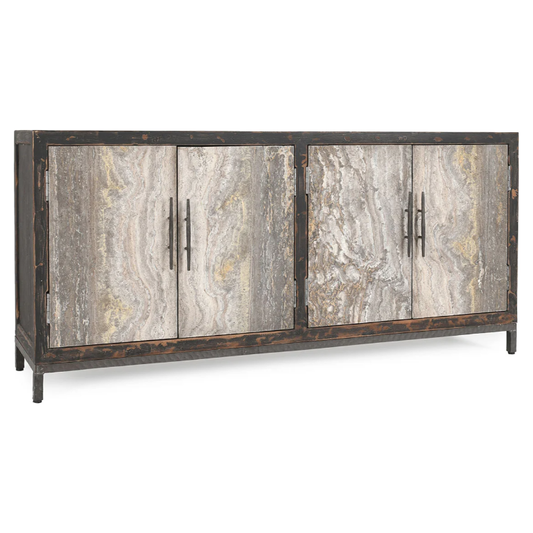 The Ember Travertine Sideboard is a rustic wooden sideboard crafted from reclaimed pine with a distressed finish that highlights the natural wood grain. It features four doors, each adorned with vertical metal handles, and the wood showcases varying shades of grey and beige for an aged, vintage appearance. The unit stands on four short legs.