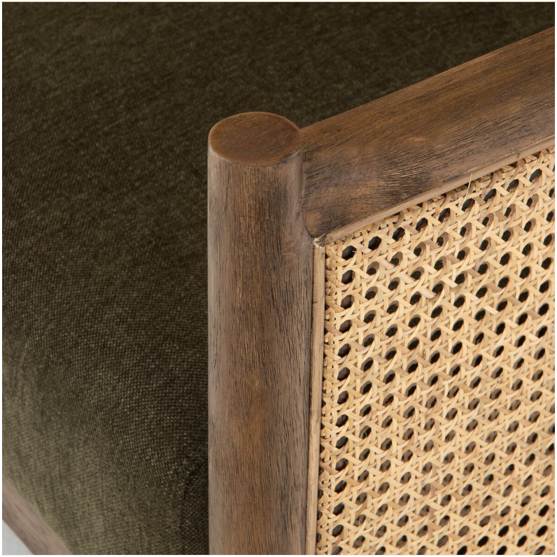 A close-up of the Julius Accent Chair reveals a dark green fabric cushion, a dark wood frame, and a woven rattan side panel. The smooth, polished finish complements the rattan's texture, adding a touch of French style elegance.