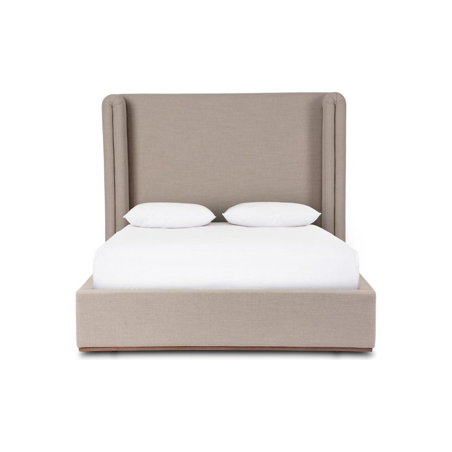 The Celeste Bed boasts a beige upholstered design with a shelter-style winged headboard, complemented by a straightforward, box-like frame. Resting on a natural wood plinth base, it features a smooth texture. Adorned with white sheets and pillows, this bed radiates minimalist modernity against its plain white background.