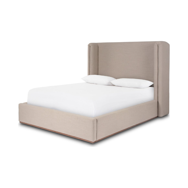 The Celeste Bed is a minimalist masterpiece characterized by its beige upholstered frame and high shelter-style headboard. It features a neatly made white mattress with two white pillows, while its natural wood plinth base enhances its modern elegance against the simple white backdrop.